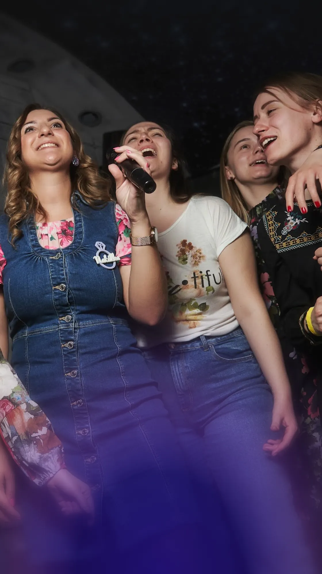 Grupo de amigas cantando karaoke alegremente con un micrófono
