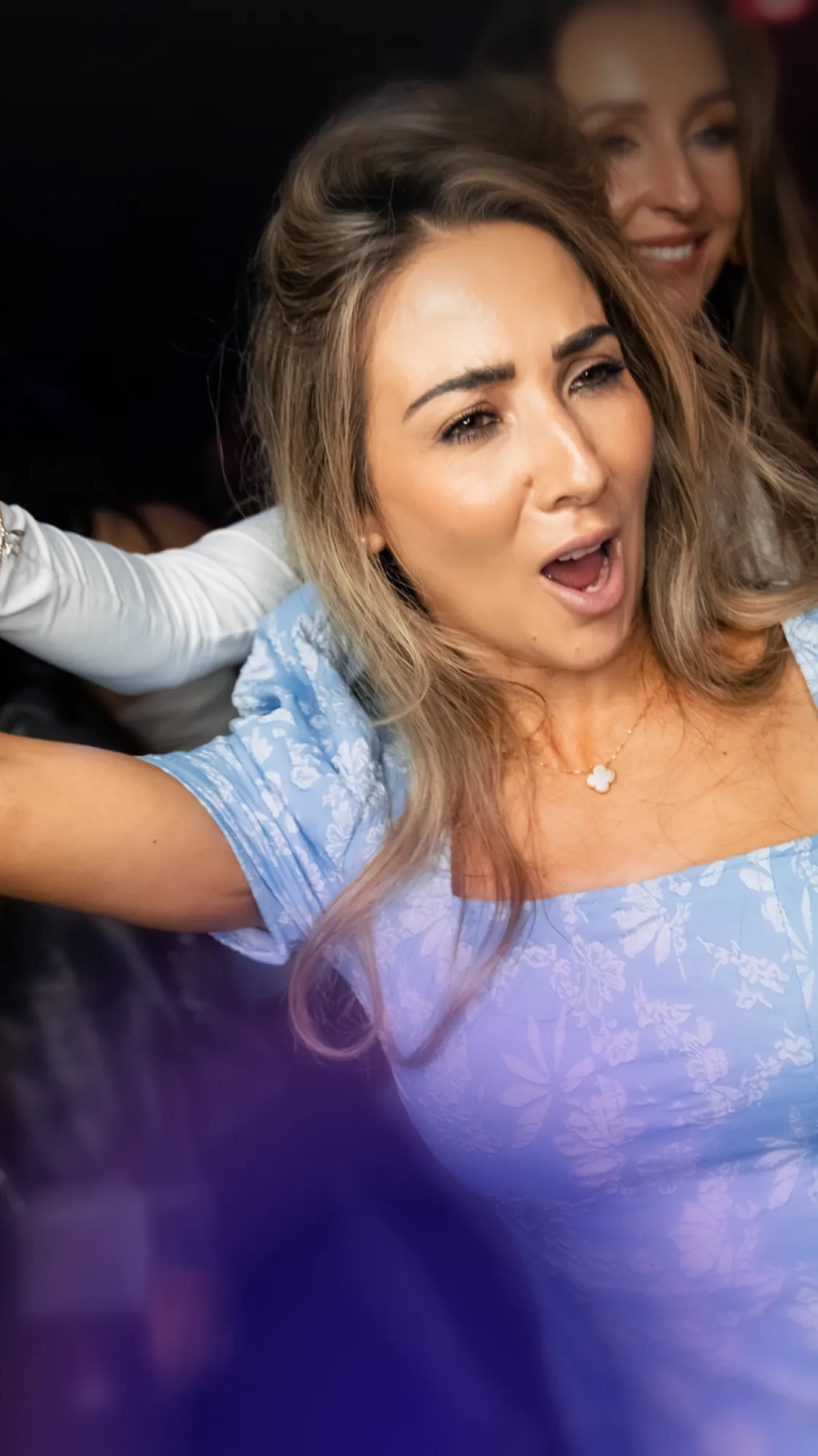A woman in a light blue dress singing passionately at a party