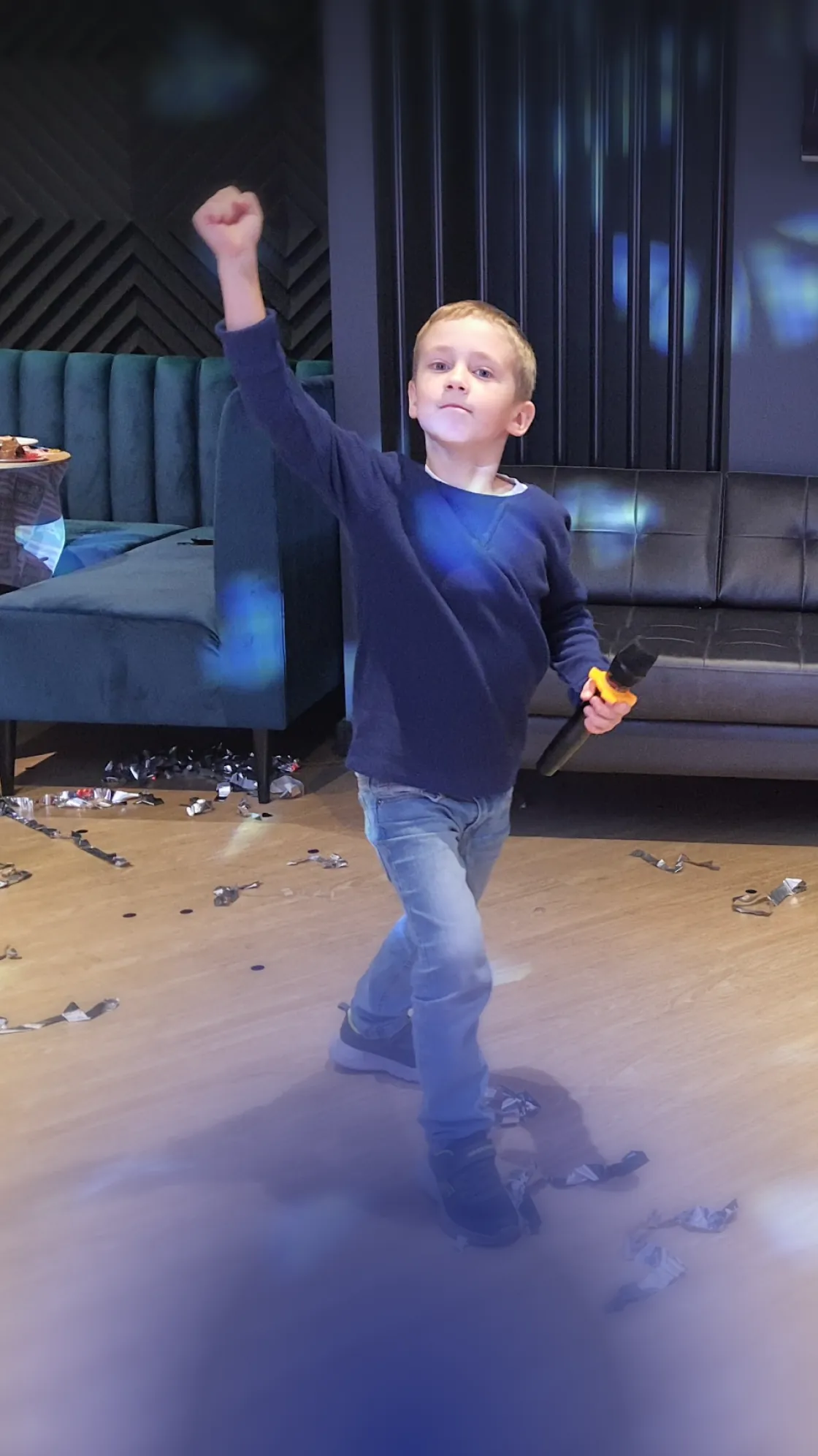 A boy with a microphone dancing happily at karaoke