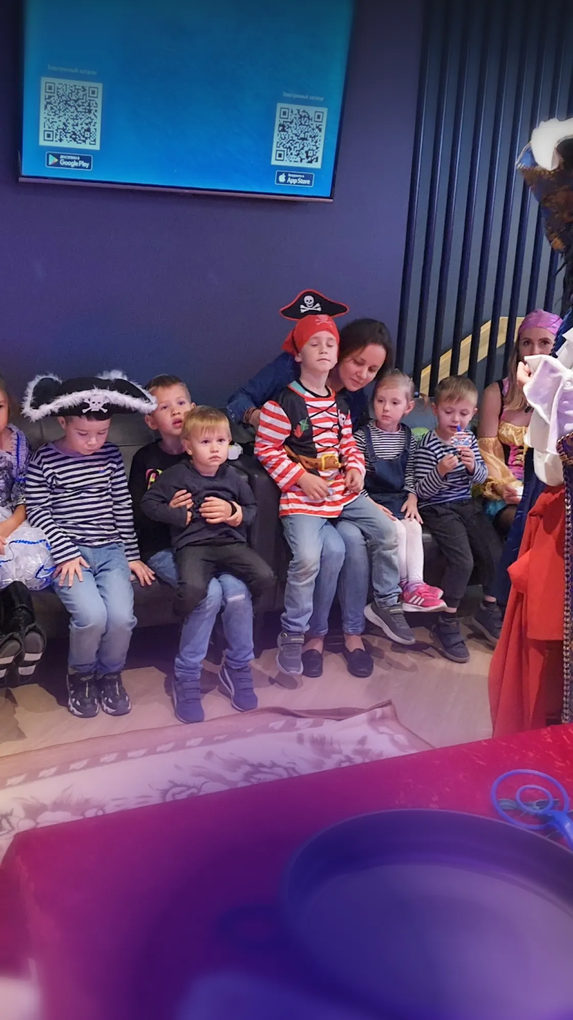 Kids in pirate costumes and a mom on a sofa at a family karaoke party