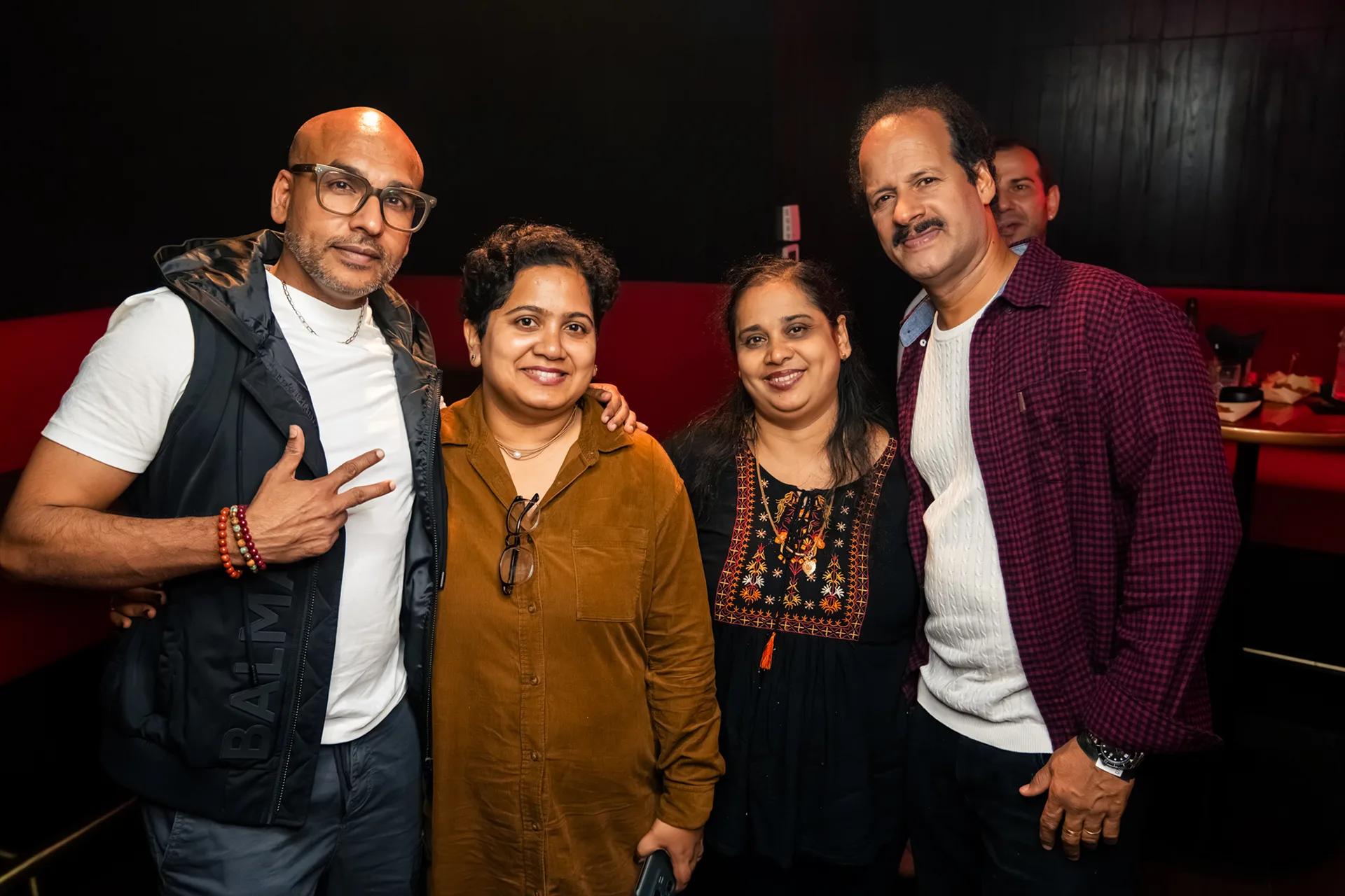 Friends and relatives smiling and posing for a photo in a karaoke room