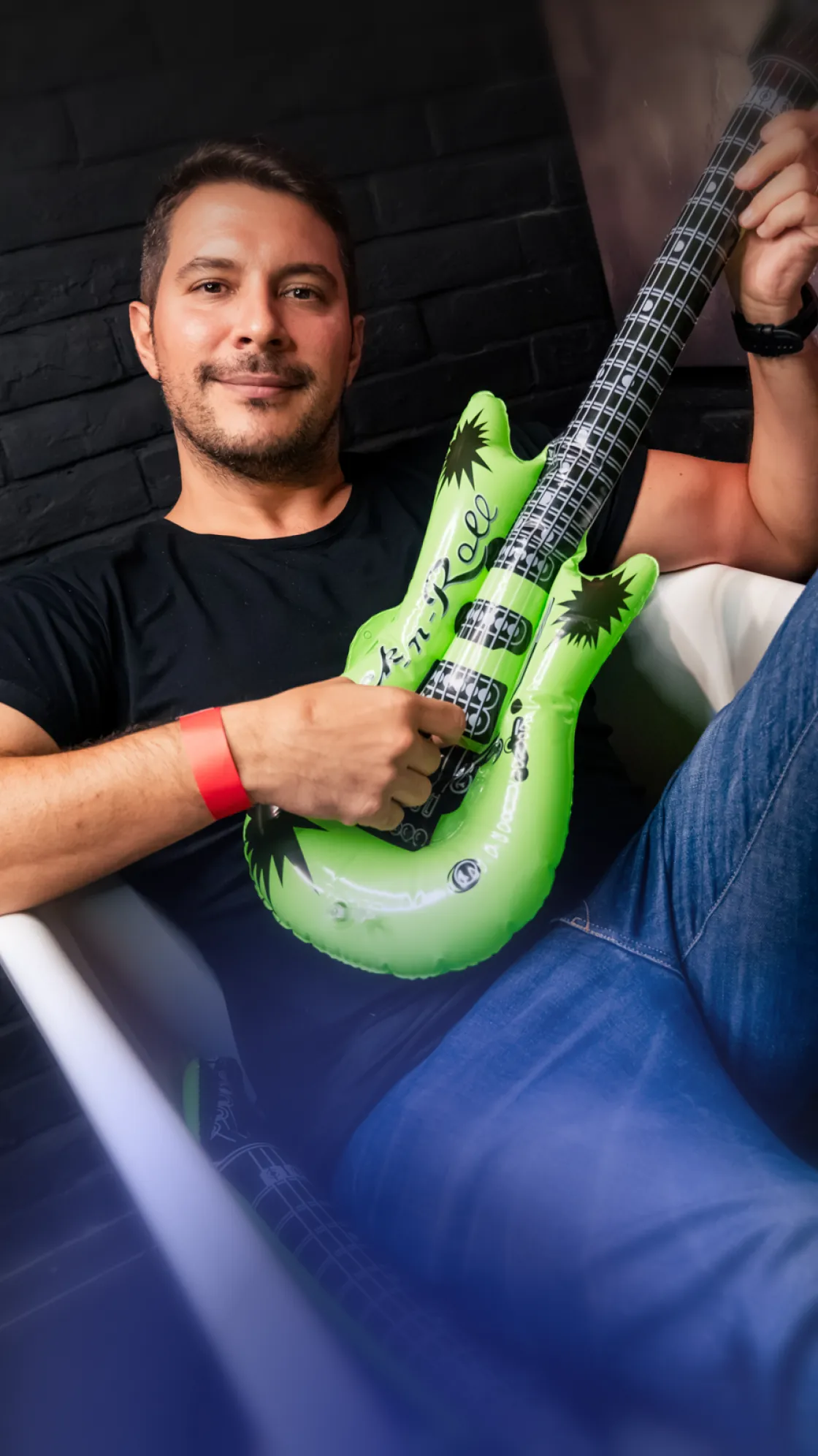 A man holding a green inflatable guitar