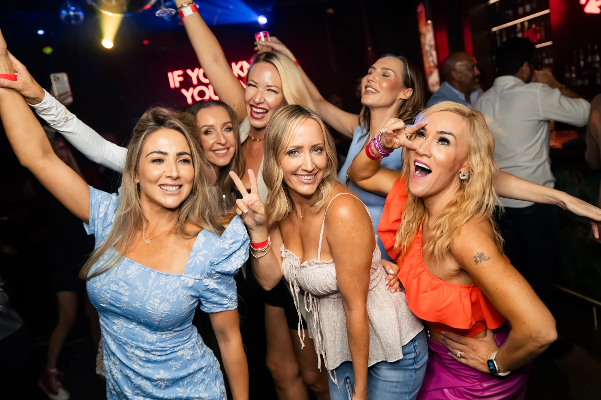 Group of girlfriends happily posing and dancing at a bachelorette party in a karaoke bar